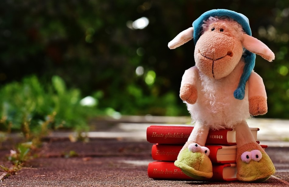 A stuffed toy sheep sitting on books